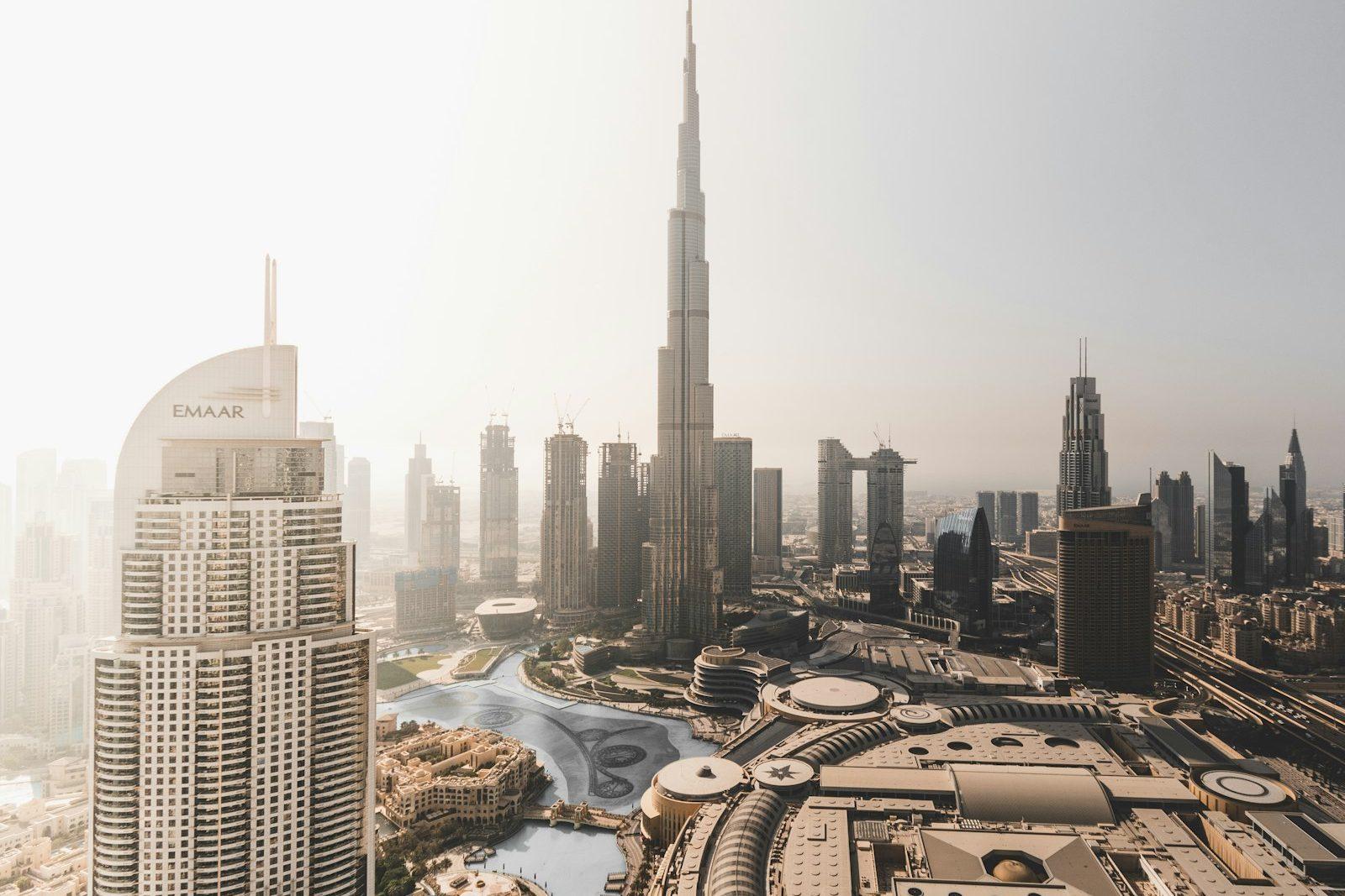 Aerial view of Downtown Dubai with the Burj Khalifa at its centre, the fountain lake and the curved roof of the Dubai Mall below.