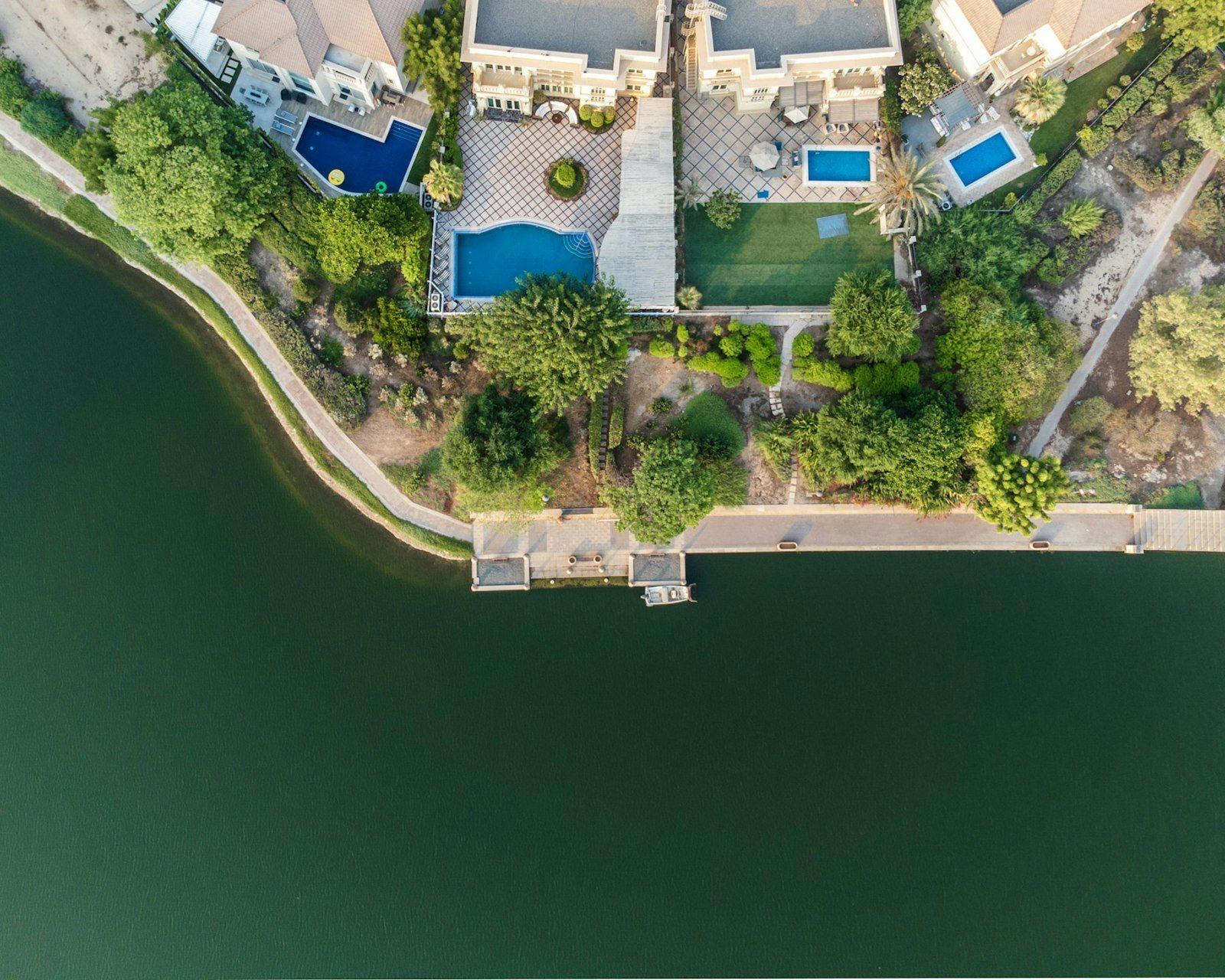 Aerial view of lakeside mansions, each with a private pool, mature planting and a lawn running down to the lake shore.