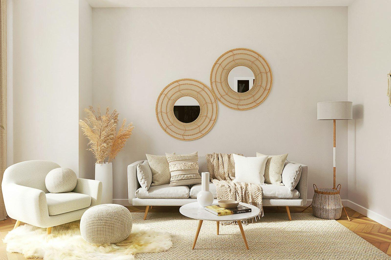 Living room in cream and natural fibre: a low white sofa and curved armchair on layered sheepskin and jute rugs, a pair of round rattan-framed mirrors on the wall and a floor lamp beside a woven basket.