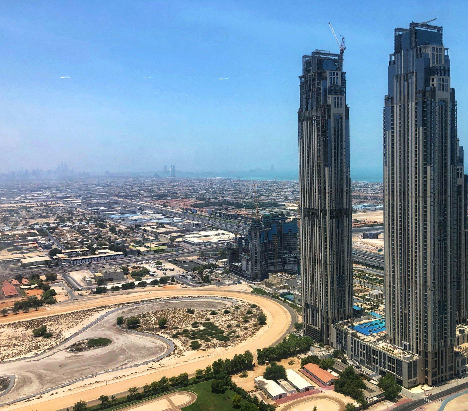 The outlook west from a high floor in Business Bay across two slender residential towers, the Nad Al Sheba racecourse below and the Gulf on the horizon.